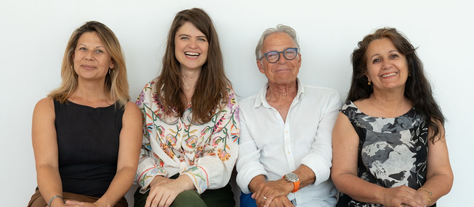 Les quatre membres du bureau de capsule.s, assis côte à côte devant un mur blanc.