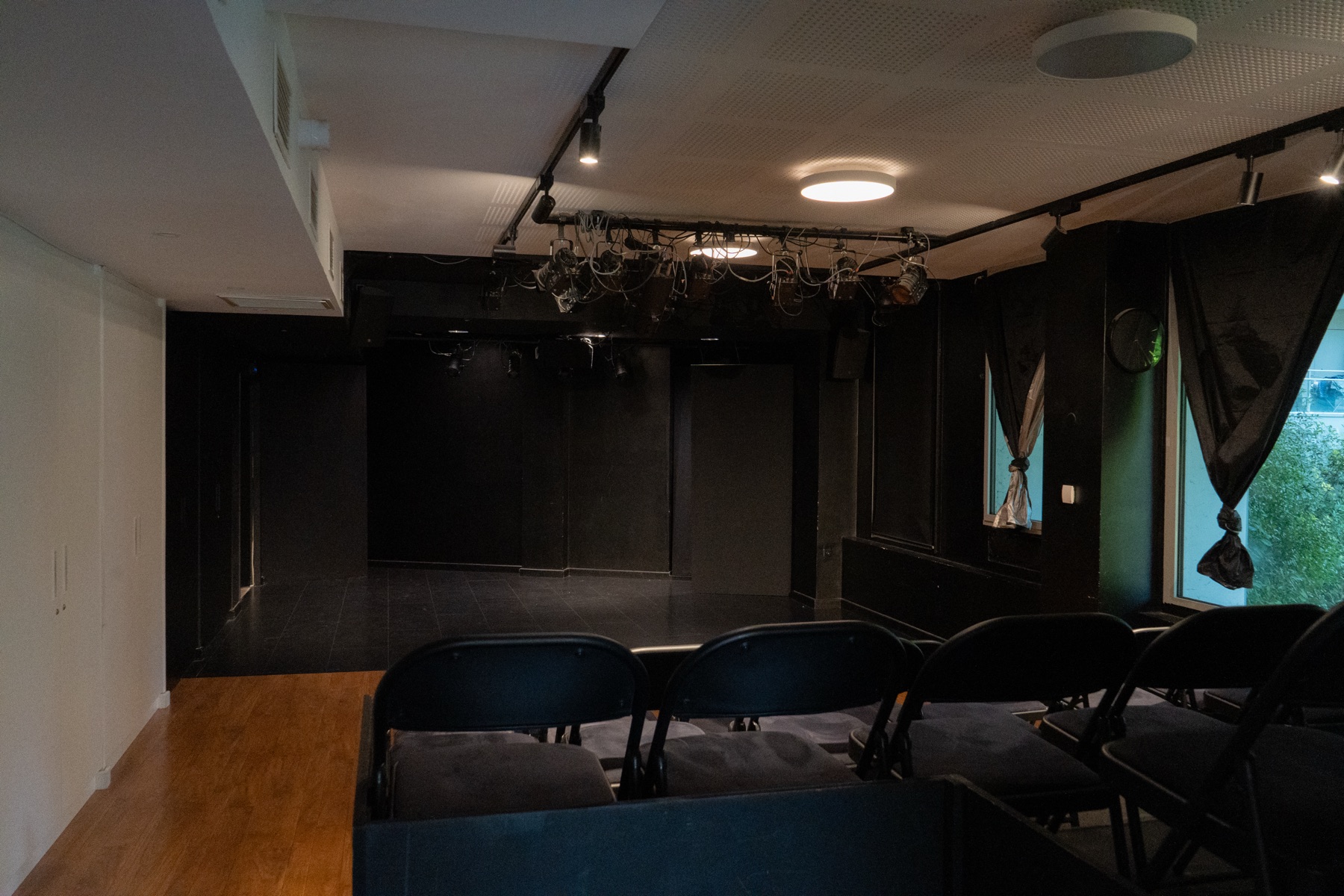 L’espace noir depuis le fond de salle : le plateau, les rideaux et la grille de projecteurs.